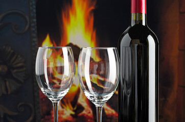 Wine bottle and wineglass on the background of the fire fireplace