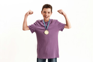 Happy teenaged disabled boy with cerebral palsy wearing gold medal, smiling at camera, raising...