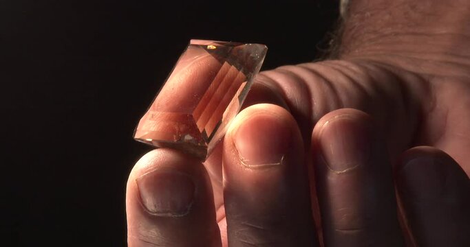 A gemologist views a flawless gem in his hand, close up