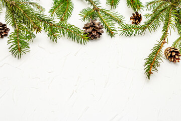 Christmas tree branches with pine cones on white putty background