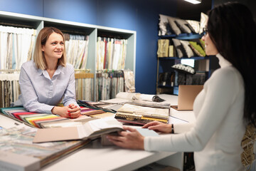 Woman consultant helping client choose curtains in workshop