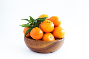 Tangerines or clementines with green leaf in a wooden bowl isolated on white background. A traditional treat for Christmas and New Years. Farm products. Healthy eating. Consumption of fresh fruits.