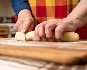 Woman cutting dough with a knife on the kitchen table