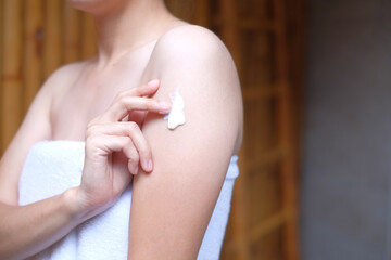 Woman applying cream,lotion on arm with wood background, Beauty concept.