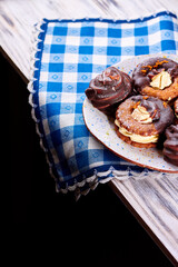 Chocolate covered marshmallow cookies on a plate on a blue and white napkin on wooden table