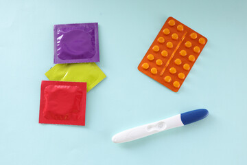 Contraceptive pills and condoms lying near pregnancy test closeup