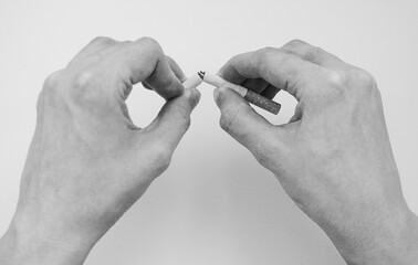 Fingers breaking a cigarette
