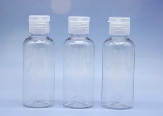 Transparent empty cosmetic bottles and jars on a soft blue background.