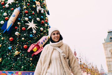 Happy woman standing next to amazing Christmas tree