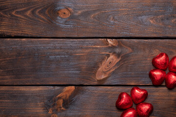 Naklejka premium Sweets with hearts on a wooden background. Red hearts made of sweets for Valentine's Day.