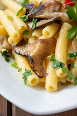 Piatto di deliziosi maccheroncini conditi con funghi, prezzemolo e peperoncino 