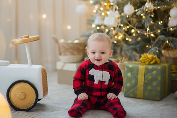 small baby sit under chrismas tree with light and presents smile