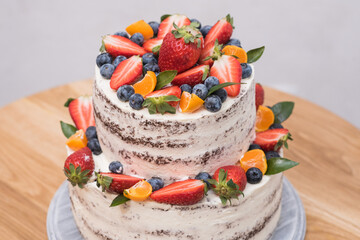 Big beautiful and delicious cake with strawberries, blueberries and tangerines