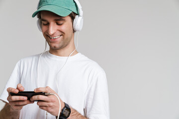 Handsome smiling guy in headphones playing online game on mobile phone