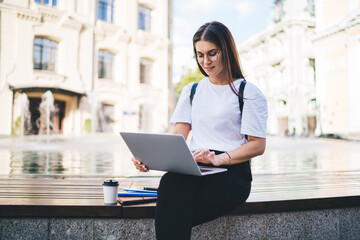 Casual dressed hipster girl in eyewear using modern laptop device for installing banking...