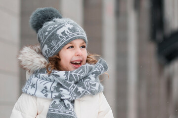 Happy little girl standing in winter city. Close up.