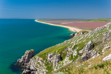 Panoramic view of the Pink lake and the sea. A strip of land separates the coast of the emerald sea and the pink lake