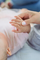 Mom holds the baby's fingers in her hand. Close up.