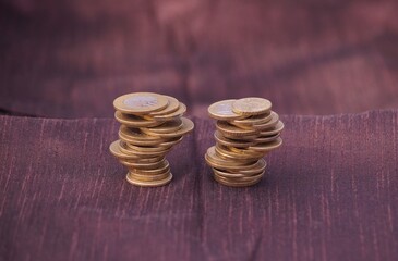 Close up shot of silver and golden stack of coins of different values on a brown background.