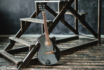 Black acoustic guitar on a dark background in loft space.