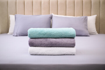 Stack of soft clean terry towels on bed