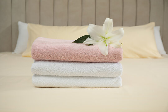 Stack of clean towels and flower on bed