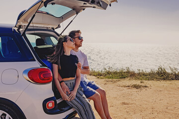 Happy young couple sitting on the trunk of the car © Diana Vyshniakova