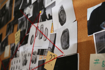 Detective board with crime scene photos, stickers, clues and red thread, closeup