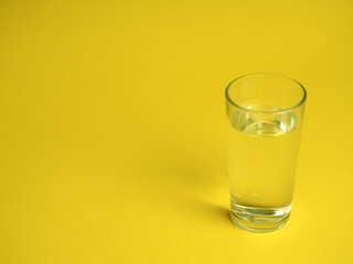 minimalistic concept of water consumption, one glass of water on a yellow background