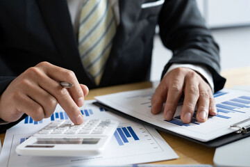 Close-up of businessmen or accountants holding a pen and pressing on the calculator to calculate business information, Finance documents, business ideas.