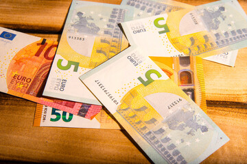 Five,ten, fifty Euro bills on a wooden table, close-up, space for text