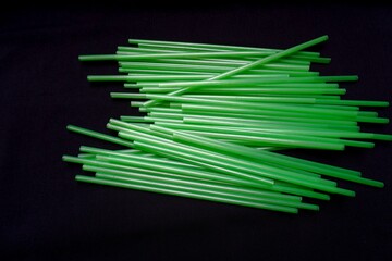 A row of green plastic straws isolated on a black background.