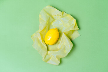Organic fabric covers for food storage. Reusable Beeswax Food Wraps lemon on green background.