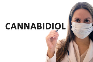 Doctor woman in a mask holds pen and writes cannabidiol text