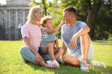 Happy parents with their child having fun on green grass. Spending time in nature