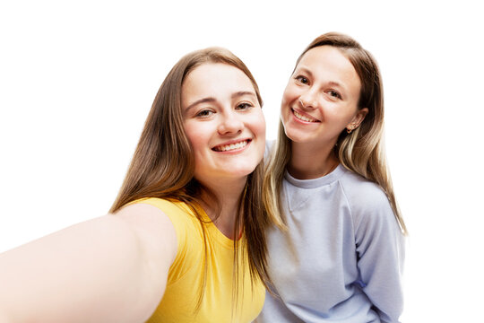Laughing young girlfriends take a selfie. Love, tenderness and friendship. Isolated on white background.