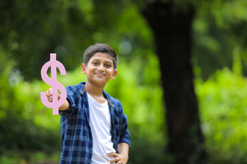 Cute indian little child holding dollar Sign on nature Background