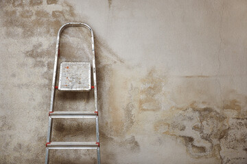 Wall renovation. Aluminum folding ladder leaning against weathered wall with copy space.