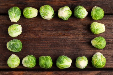 Frame made with Brussels sprouts on brown wooden table, flat lay. Space for text