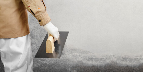 Construction worker with trowel ready to repair a weathered wall. House renovation web banner...