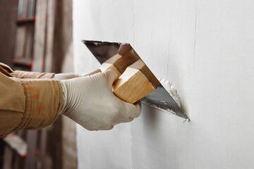 Hands of construction worker plastering and smoothing wall with a trowel. House renovation concept. 