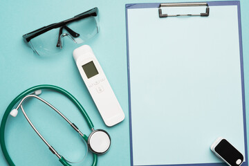 pulse oximeter and electronic thermometer and other medical supplies on a blue background,