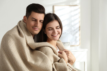 Obraz premium Happy couple covered with warm beige plaid indoors