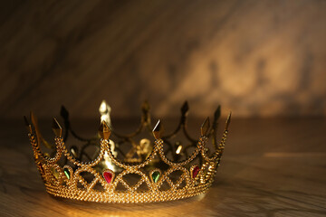 Beautiful golden crown with gems on wooden table. Fantasy item © New Africa