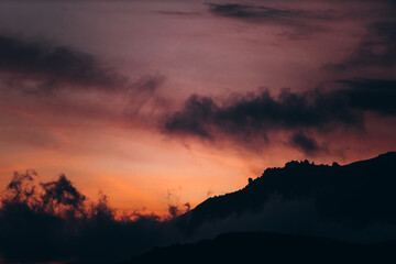 saturated orange-purple mountain landscape with clouds during twilight.