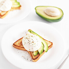 Toast with poached eggs and avocado. Healthy breakfast and food. Cozy morning. Nutrition for pregnant. Diet for women. Breakfast in hotel room or bed. Scrambled eggs sandwich.