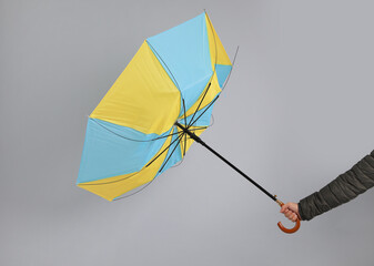 Man holding umbrella caught in gust of wind on grey background, closeup