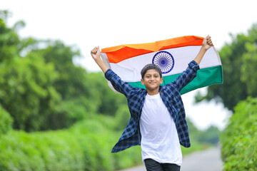 Cute little boy waving Indian National Tricolor Flag over nature background