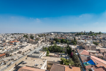 Fototapeta na wymiar Aerial view of rooftops of traditional buildings and Hurva Synagogue in the old city with blue sky of Jerusalem. View from the Lutheran Church of the Redeemer.
