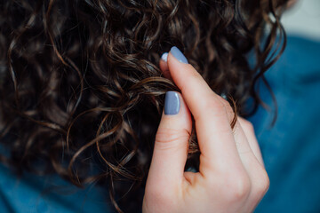 Woman's hand touching long curly hair